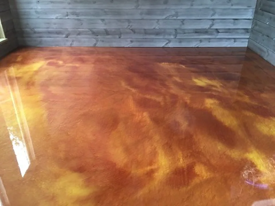 Amber and gold metallic epoxy floor against a grey wood wall