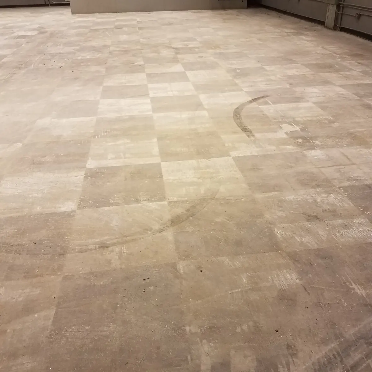 Shop floor before: bare, stained concrete with tile ghosting