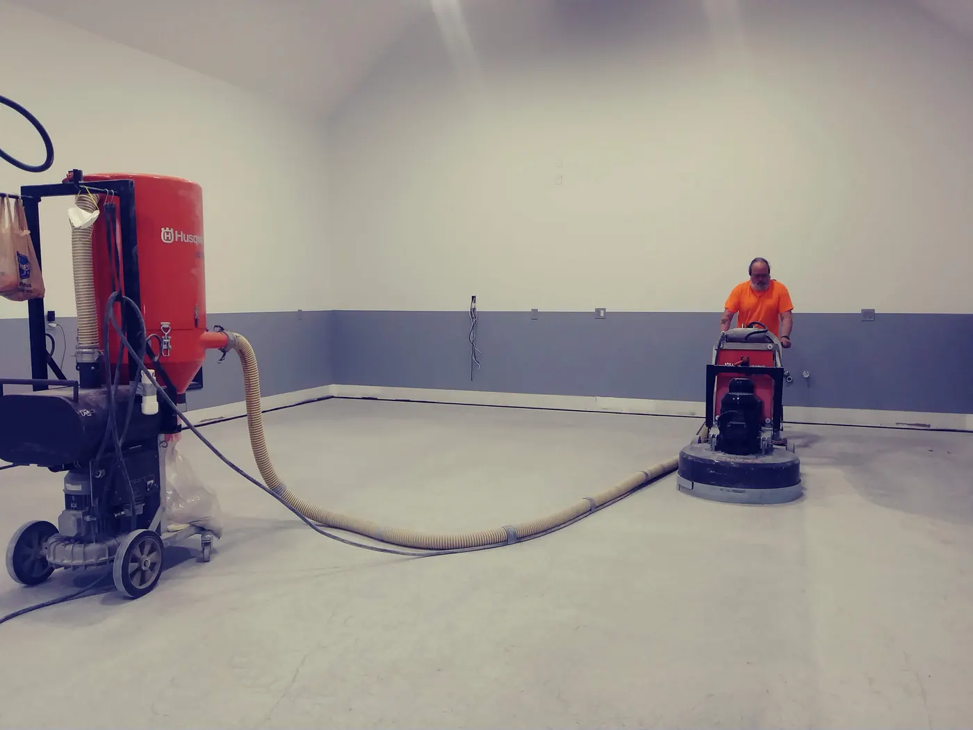 Diamond grinder and HEPA vacuum at work on a concrete slab