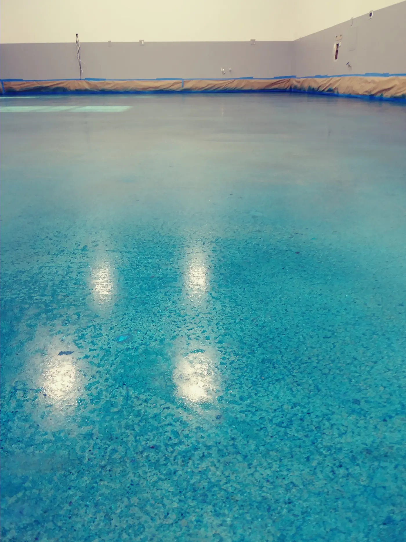 Blue metallic epoxy floor with reflections from overhead lights